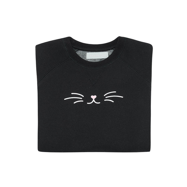 A folded black sweatshirt with a white and pink cat face print on the front.